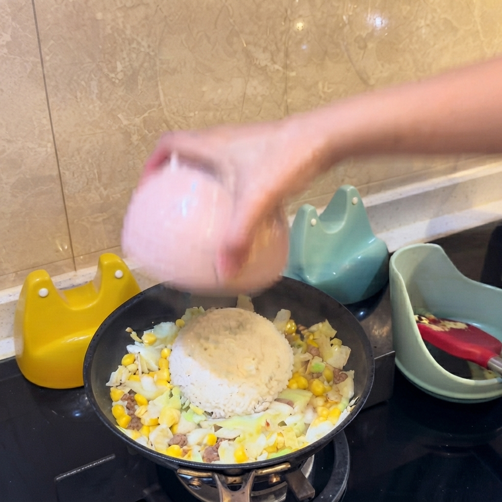 Un bol rose retournant un monticule de riz blanc directement au centre des ingrédients de la poêle.