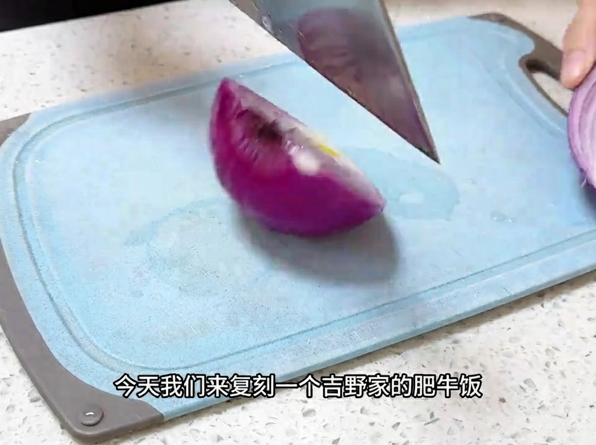 Un couteau de cuisine coupant un oignon rouge en fines lamelles sur une planche à découper bleue.