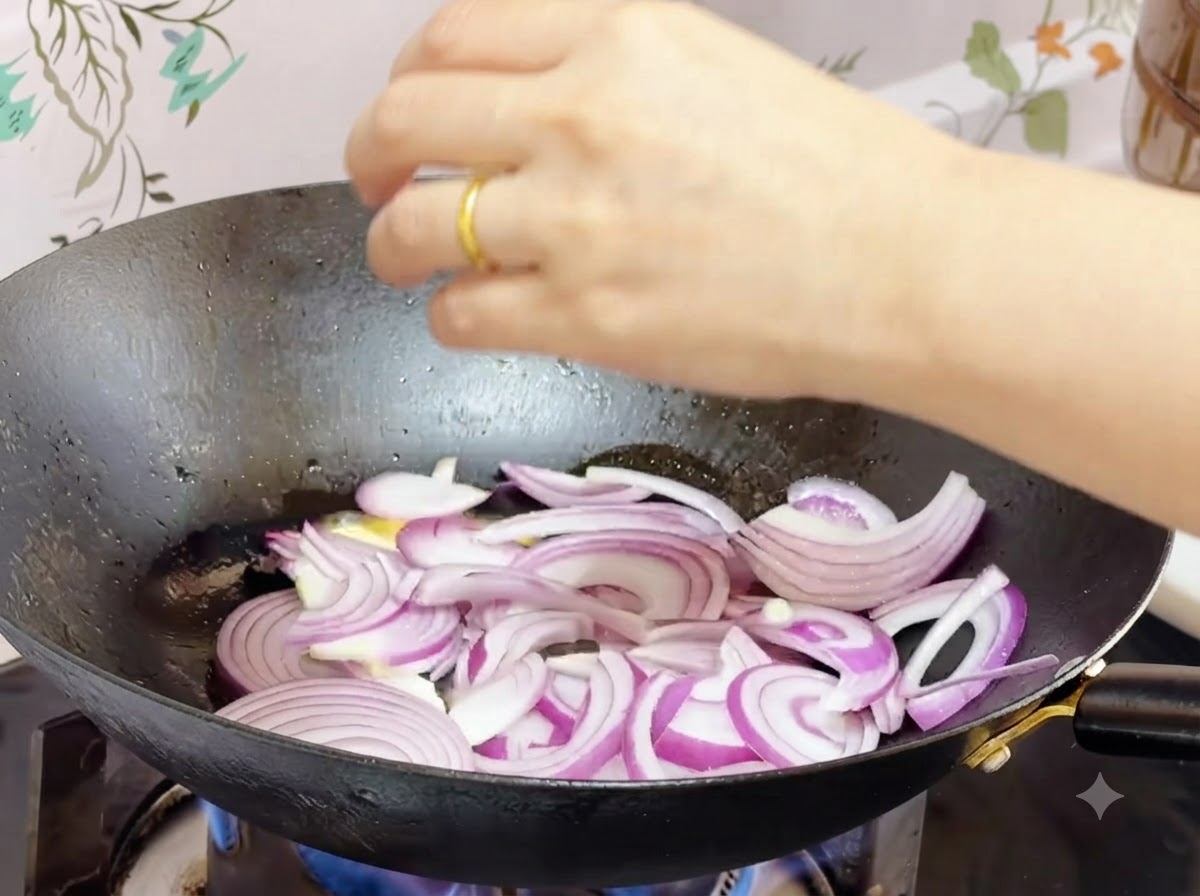 Des oignons rouges émincés en train de sauter dans du beurre fondu à lintérieur dun wok.