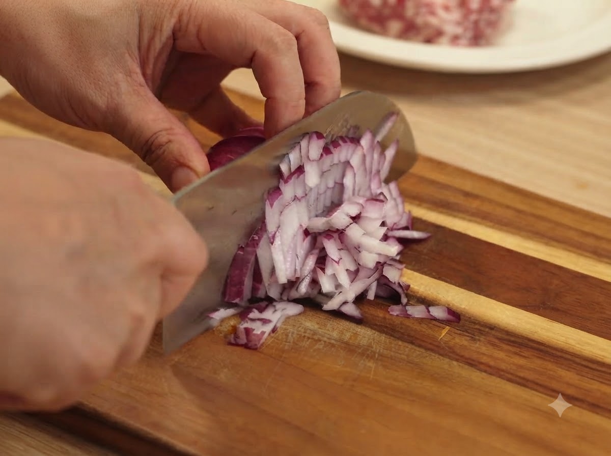 Des gousses dail émincées finement avec un couteau sur une planche à découper en bois.
