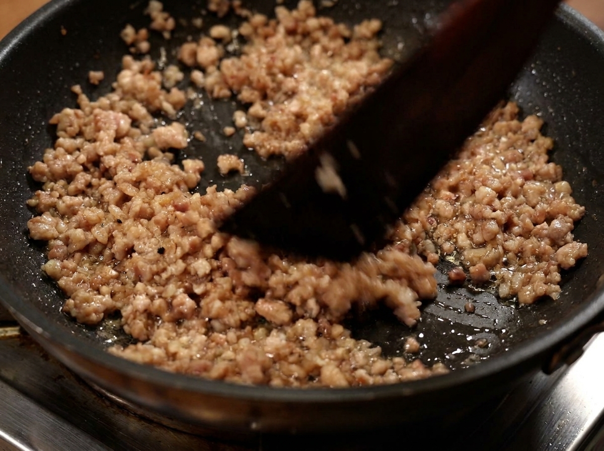 Du porc haché cuit retiré dune poêle à frire à laide dune spatule.