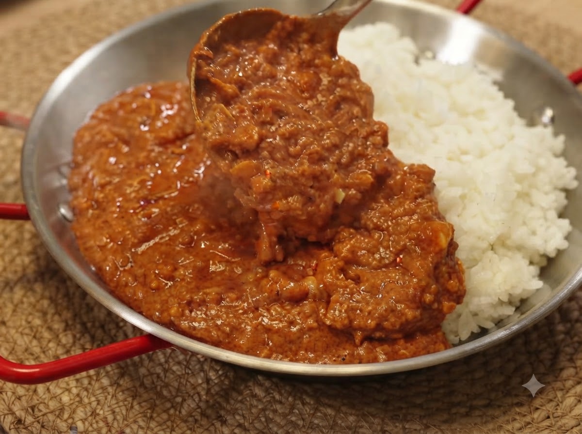 Une louche servant de la sauce au porc haché au curry riche sur un lit de riz blanc dans une poêle de service.
