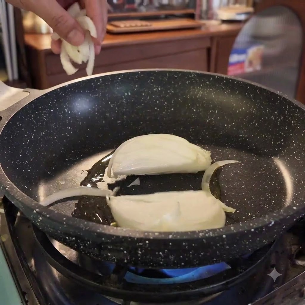 Des tranches doignon sont ajoutées dans une poêle chaude huilée sur une flamme bleue.