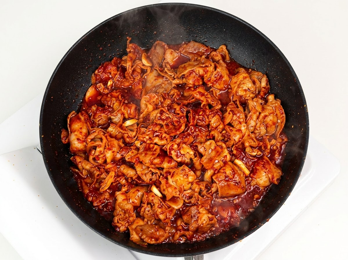 Oignon blanc émincé ajouté dans la poêle avec le porc sauté en sauce.