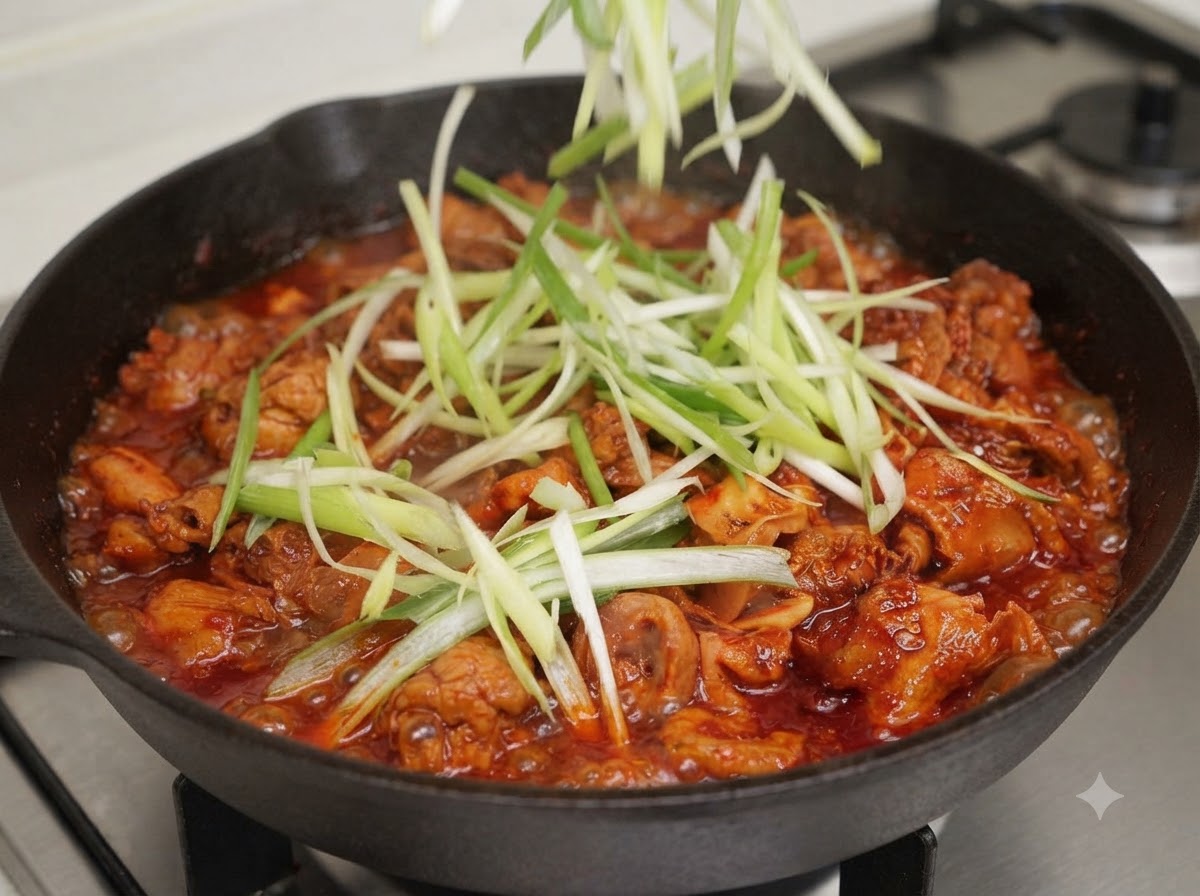 Ciboules émincées et lanières de piment vert ajoutées par-dessus le mélange de la poêle.