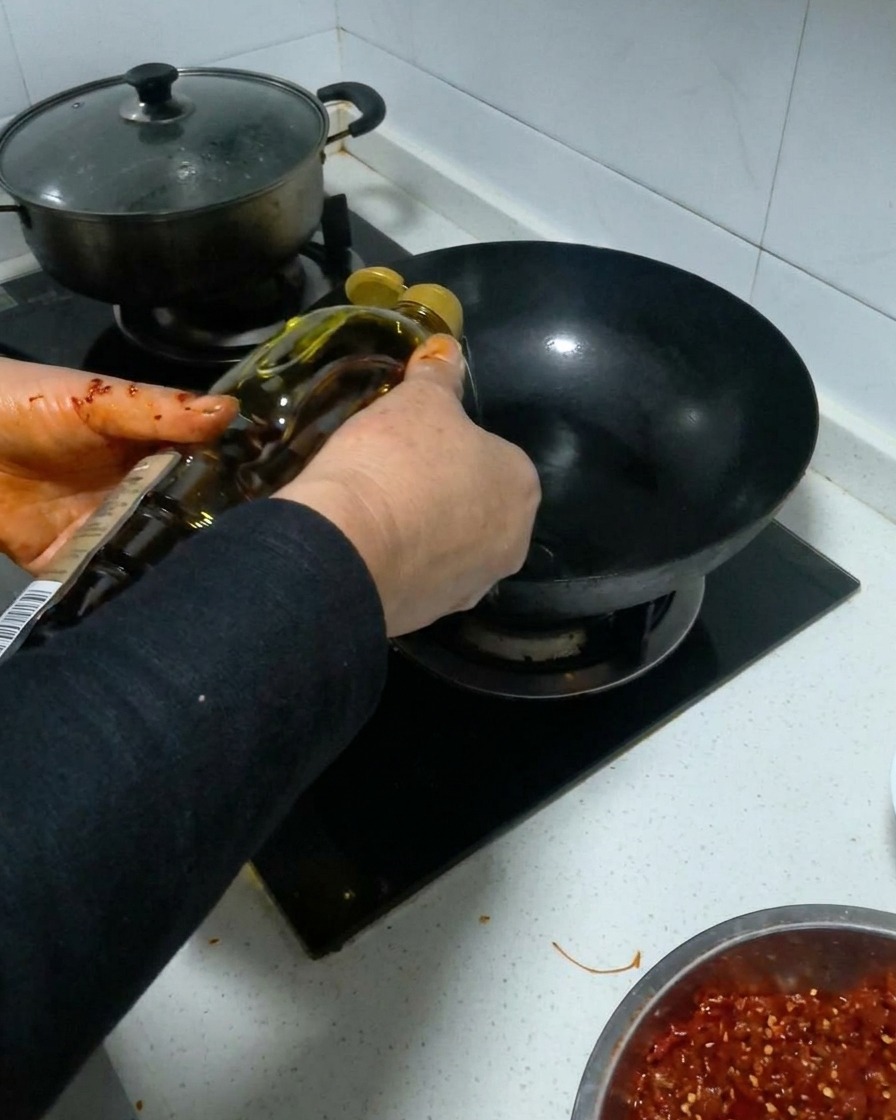 Huile de cuisson versée dune bouteille dans un wok noir chauffé.