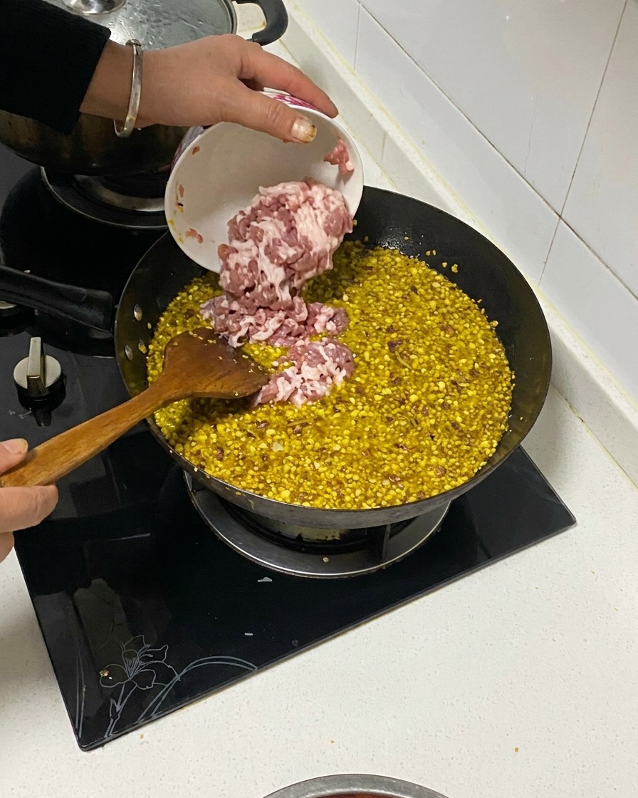 Poitrine de porc en dés versée dun petit bol dans un wok contenant des aromates frits et de lhuile.