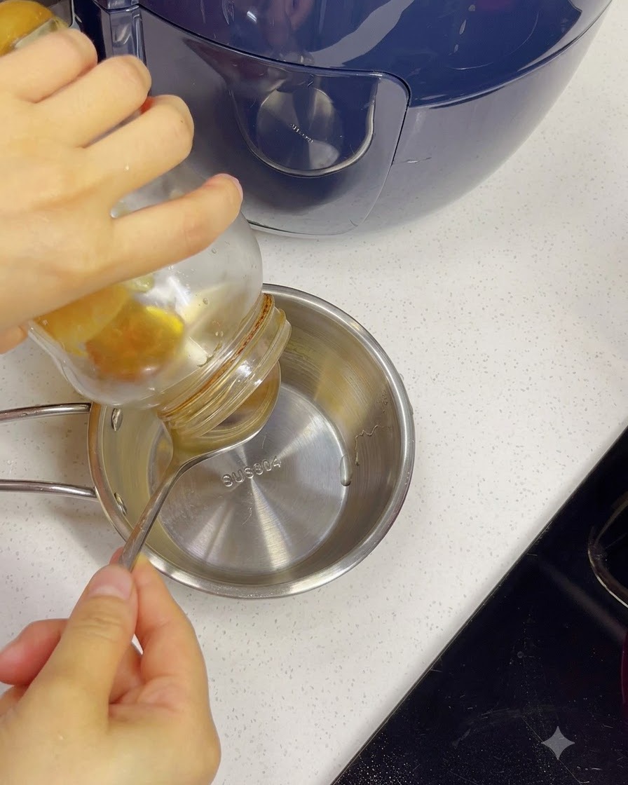 Du miel versé dun pot dans un petit bol en acier inoxydable contenant de leau à laide dune cuillère.