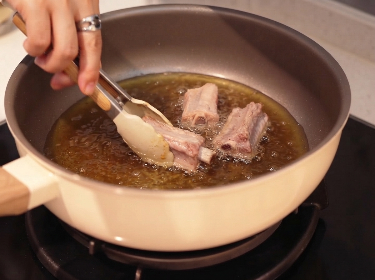 Côtes de porc en train dêtre poêlées dans de lhuile chaude à laide de pinces.