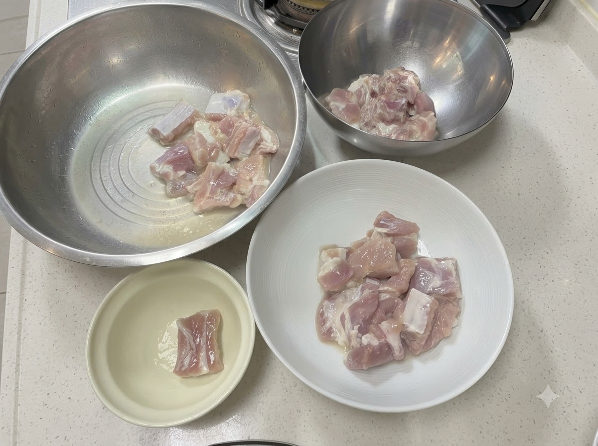 Morceaux de côtes de porc disposés dans divers bols en métal et en céramique sur un plan de travail blanc.