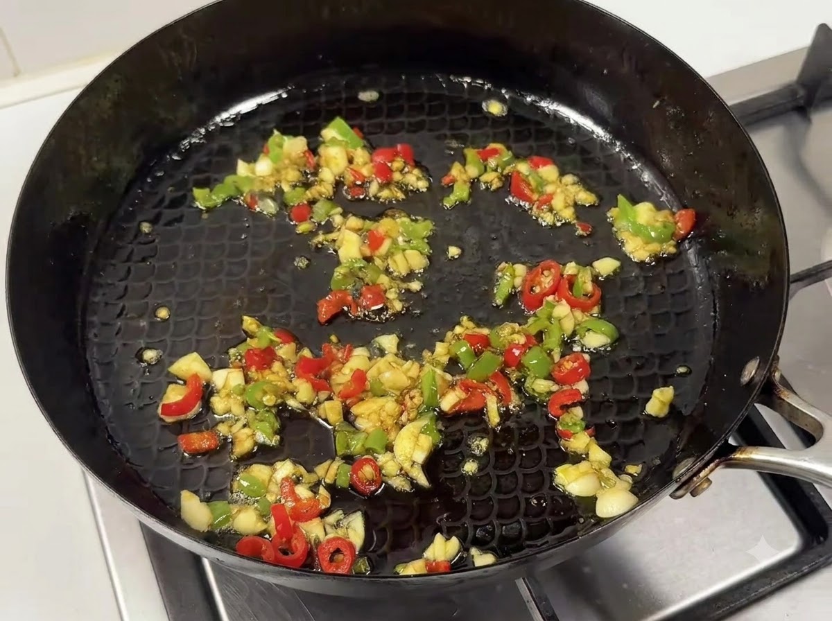Une poêle contenant le mélange dail et de piments sautés mélangé à un savoureux mélange de sauces.
