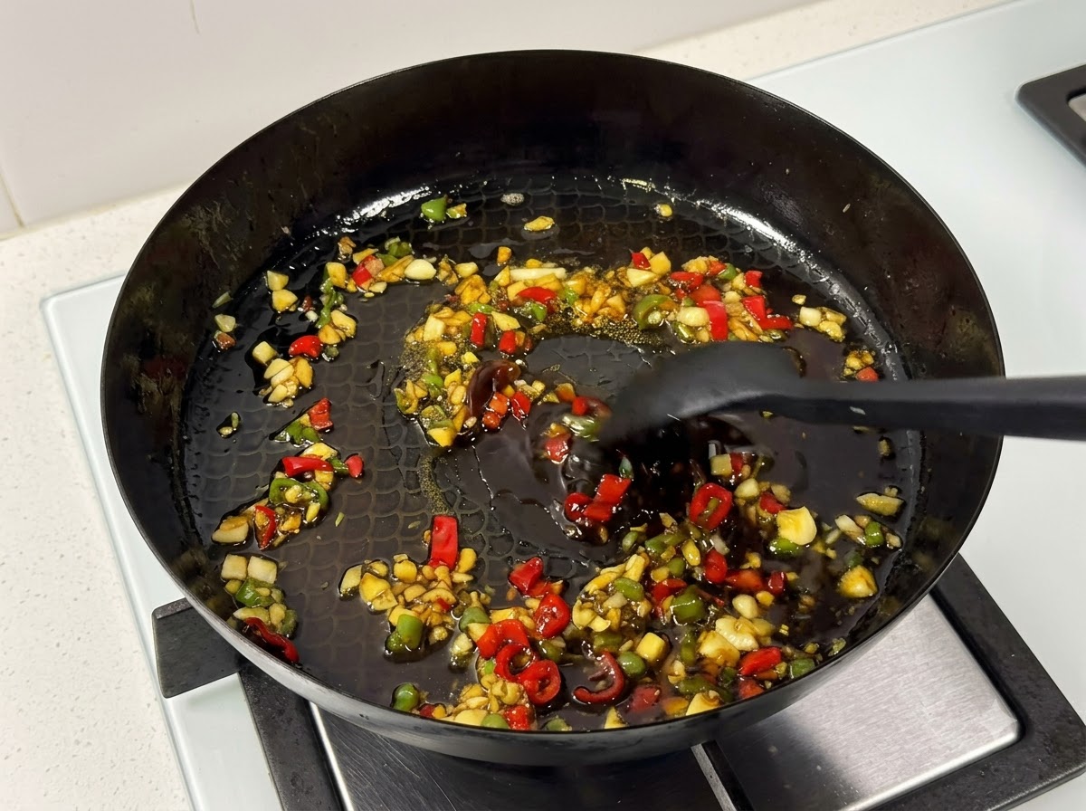 Une spatule de cuisine remuant les travers de porc et la sauce dans une poêle sur la cuisinière.
