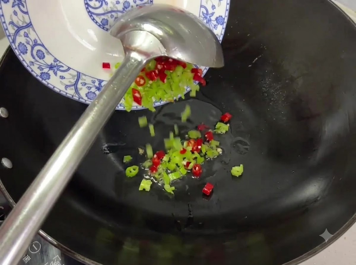 Des morceaux de piments rouges et verts versés dune assiette dans un wok avec de lhuile.