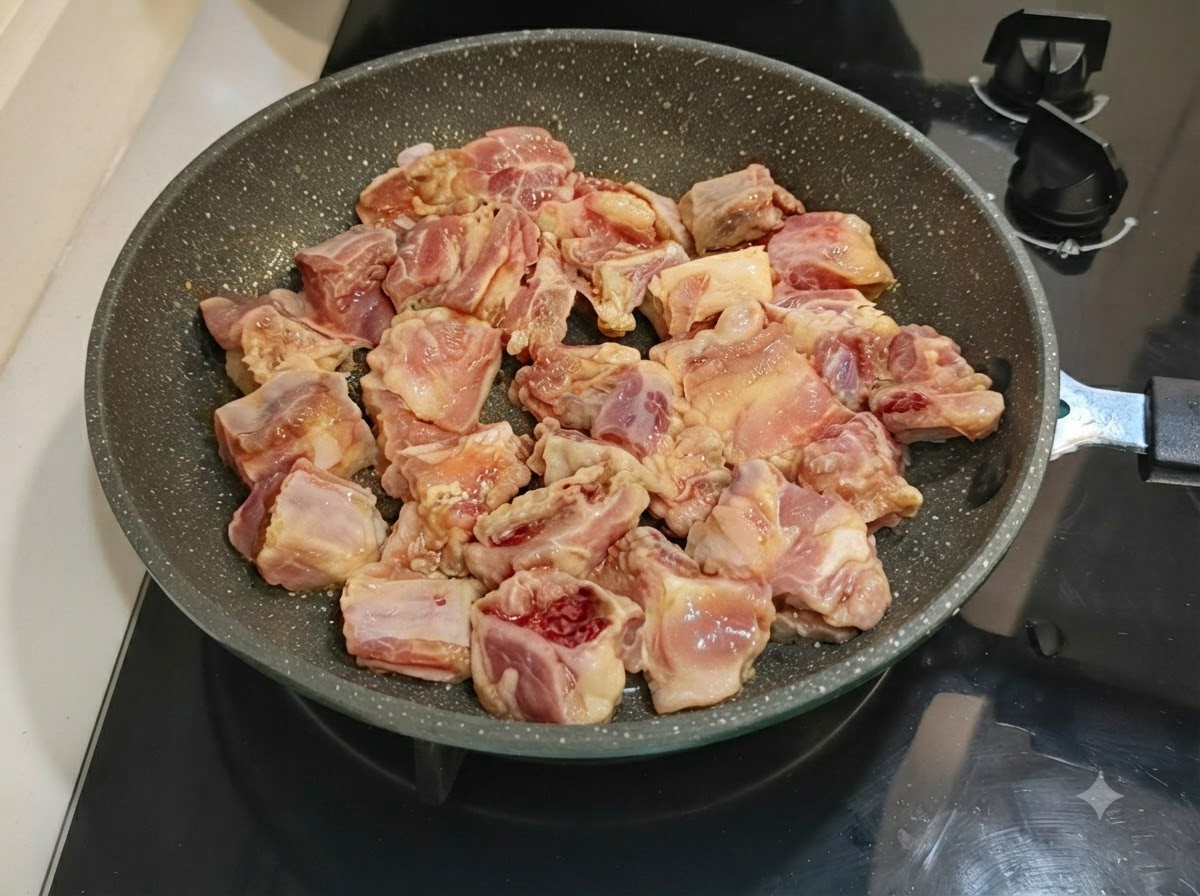 Côtes de porc marinées disposées soigneusement dans une poêle à frire mouchetée posée sur une cuisinière.