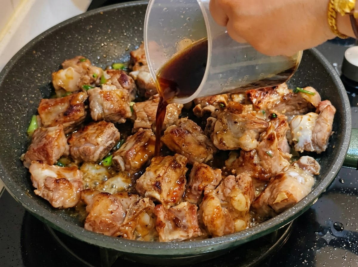 Sauce foncée versée dun tasses à mesurer dans la poêle avec les côtes de porc.