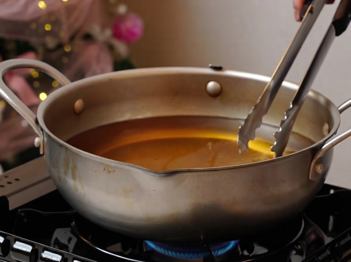 Travers de porc frisant doucement dans une grande casserole dhuile sur un brûleur.