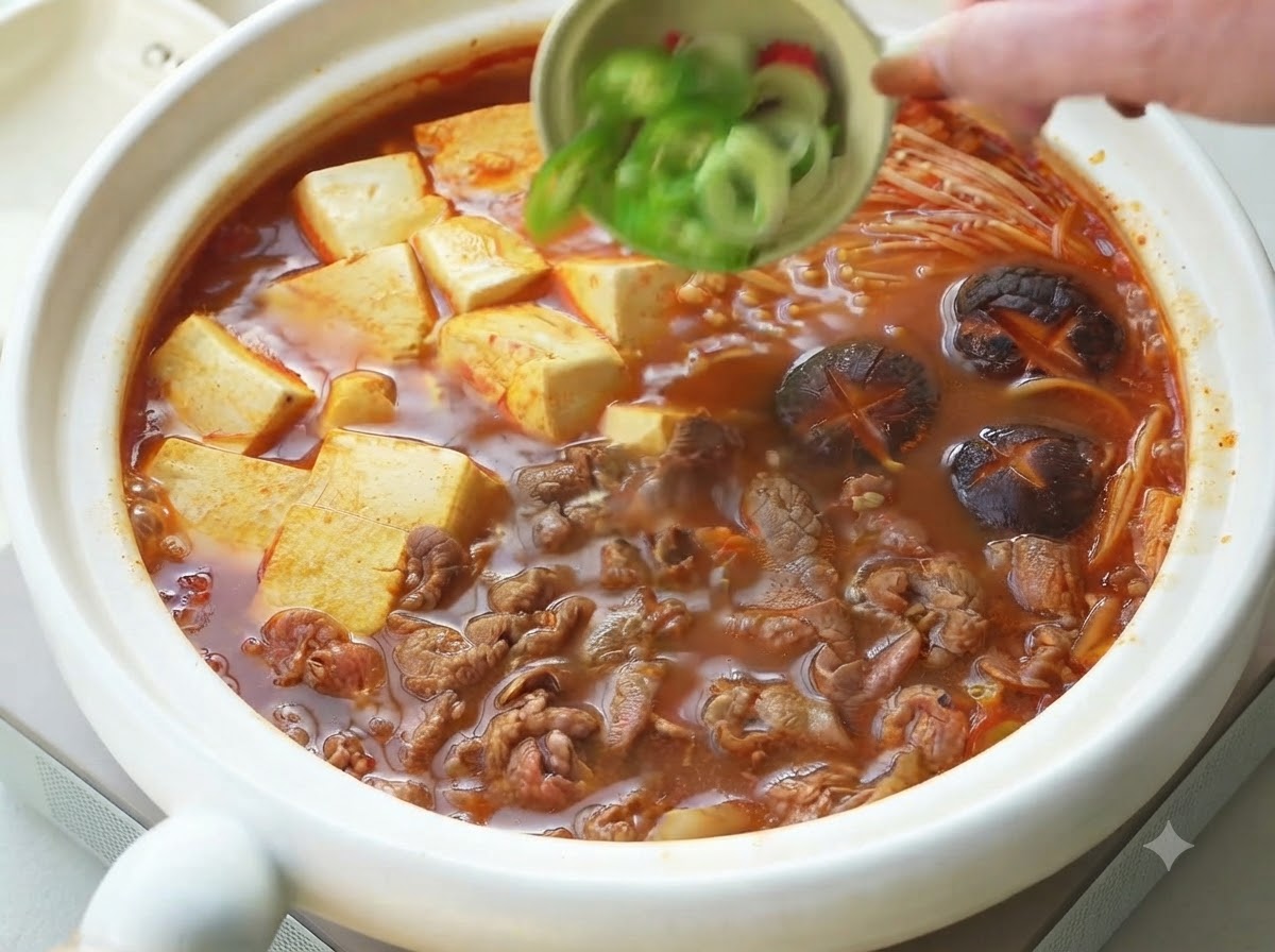 Oignons verts et piments émincés versés dun petit bol en guise de garniture sur le ragoût coréen de bœuf et tofu cuit.