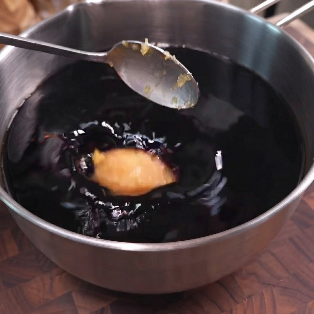 Une cuillerée dail haché versée dans un bol de marinade à base de sauce soja foncée.