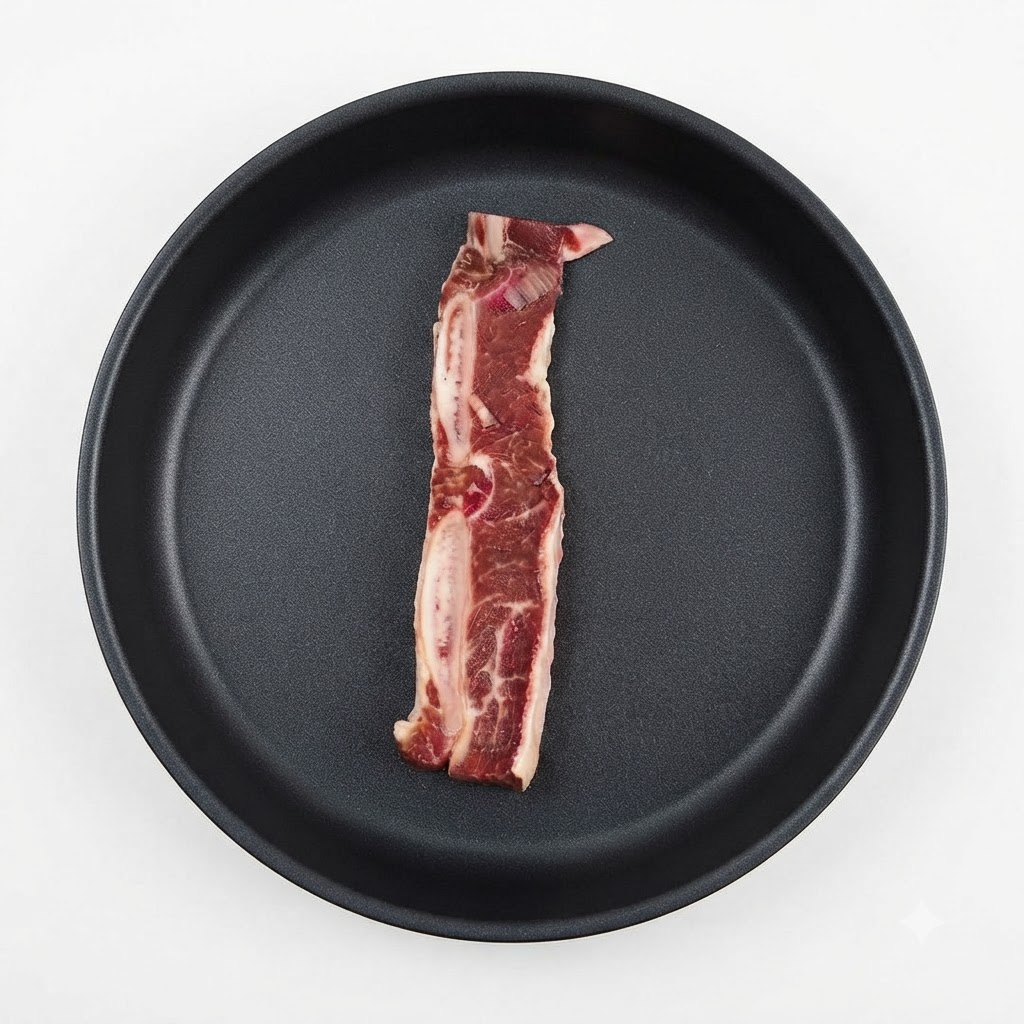 Un seul morceau de côte de bœuf marinée placé à lintérieur dune poêle sombre.