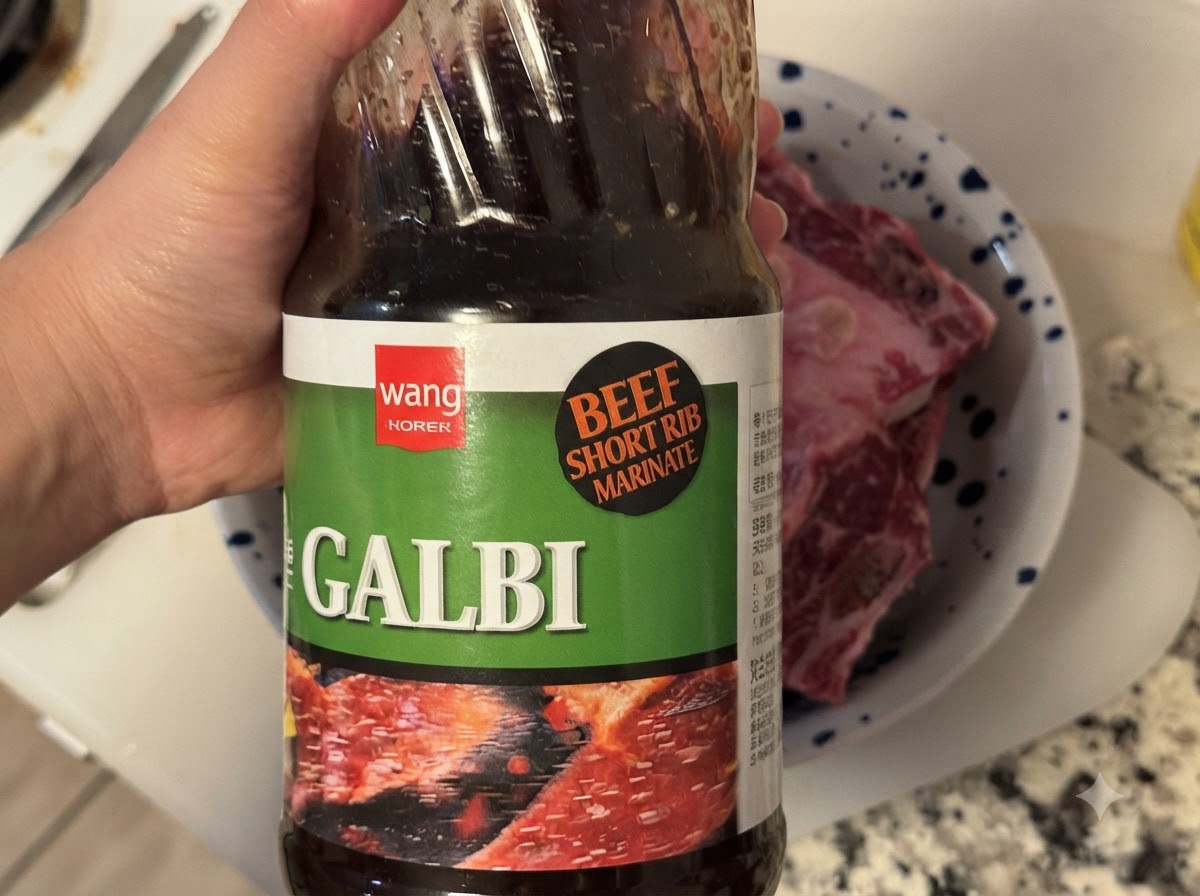 Une bouteille de sauce BBQ coréenne Galbi versée dans un bol contenant des côtes de bœuf crues.