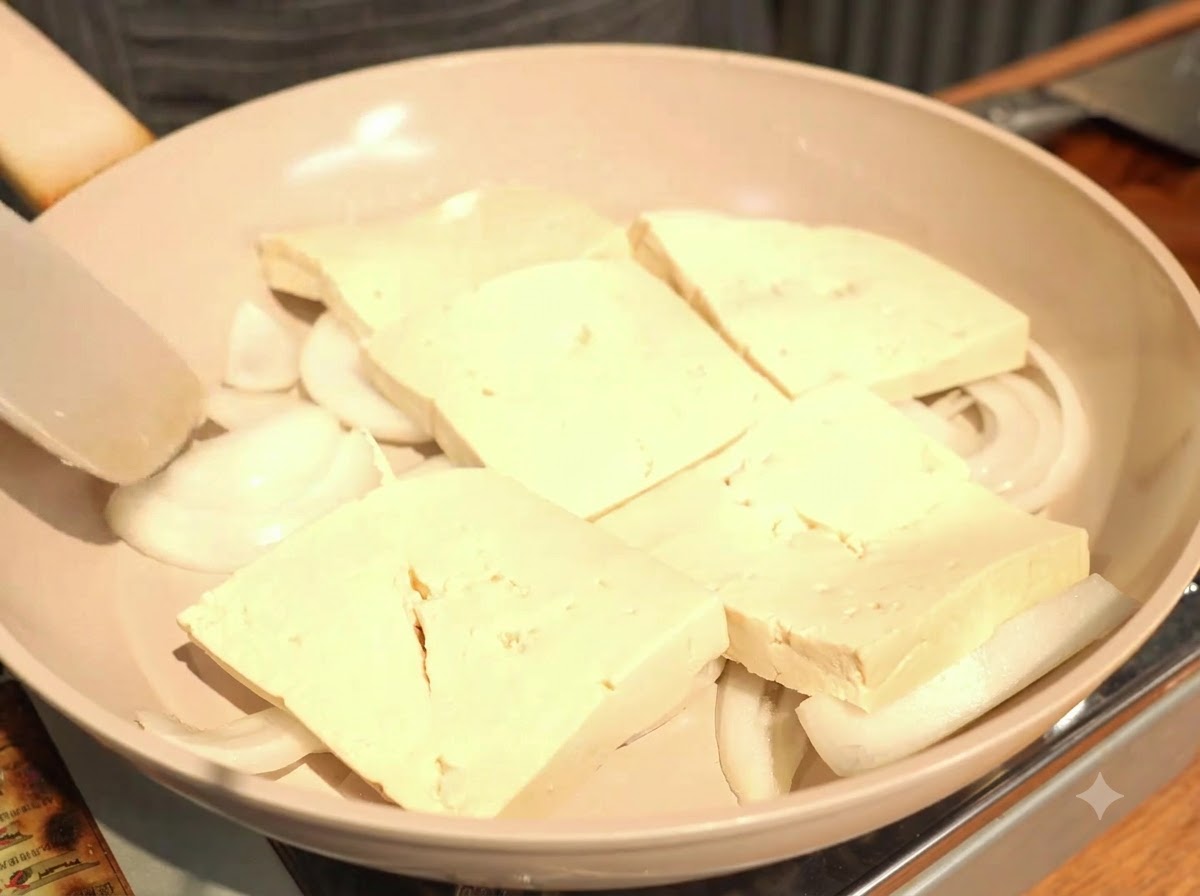 Tranches épaisses de tofu disposées en une couche recouvrant légèrement les oignons.
