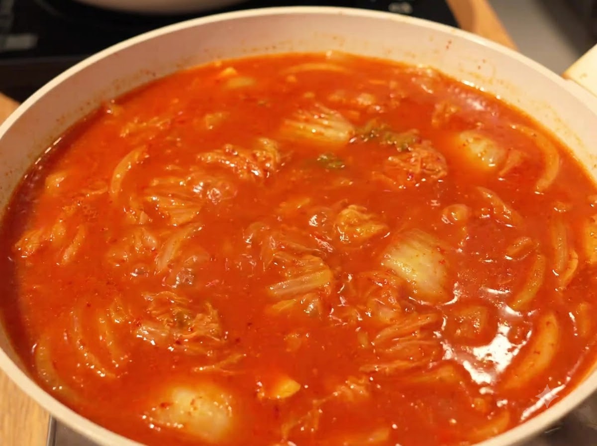 Bouillon rouge riche et frémissant avec le tofu et les garnitures dans une poêle sur le feu.
