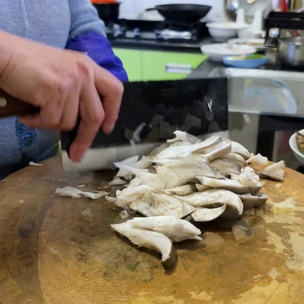Des champignons pleurotes coupés en morceaux sur une planche en bois à laide dun couteau chinois.