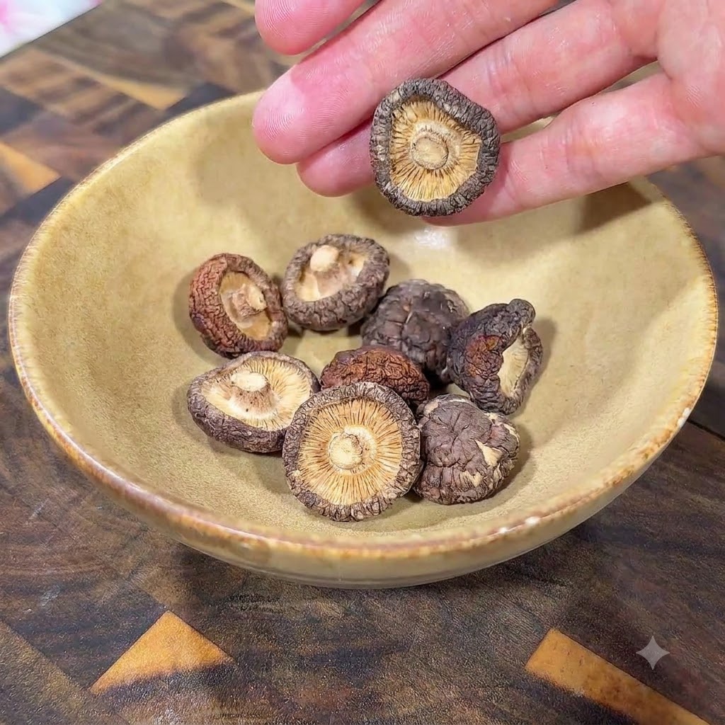 Des champignons shiitake séchés disposés dans un bol en céramique jaune sur une surface en bois.