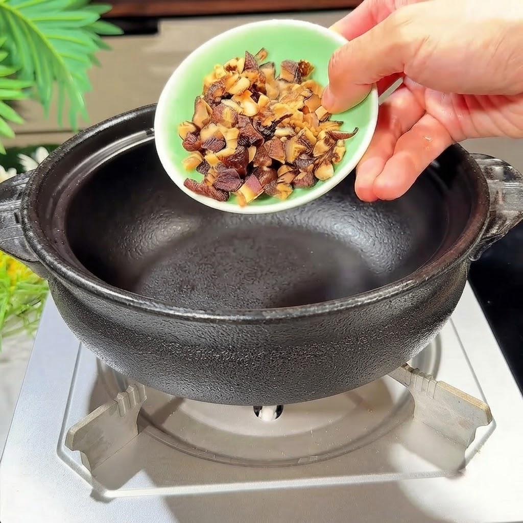 Des champignons shiitake en dés versés dans un pot en argile noire chauffé.