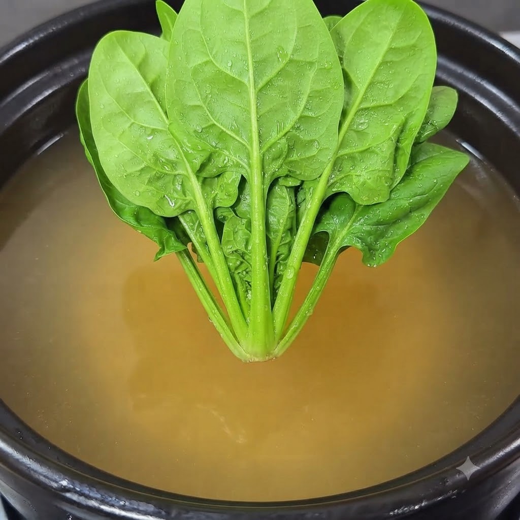 Un bouquet dépinards frais positionné au-dessus du pot de cuisson.