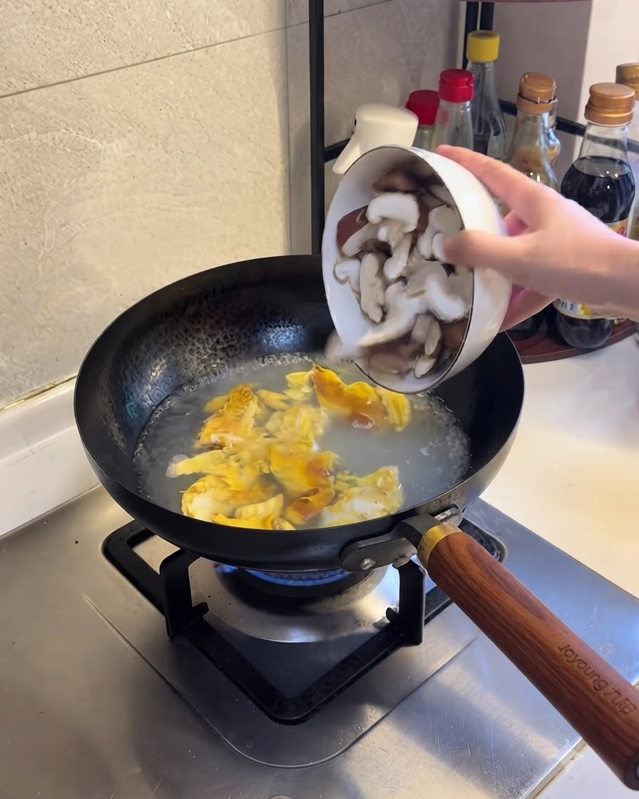Des tranches de champignons shiitake ajoutées à leau bouillante et au mélange dœufs.