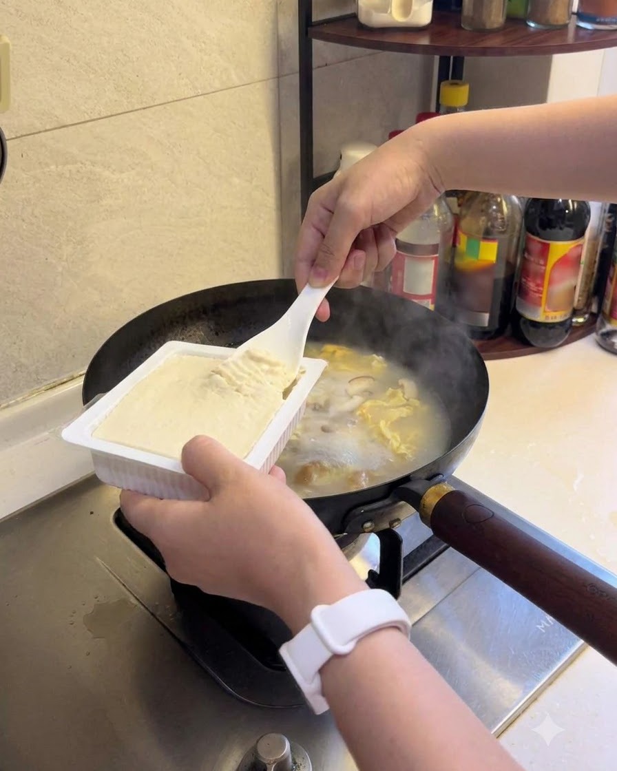 Du tofu soyeux ajouté dans la soupe frémissante.
