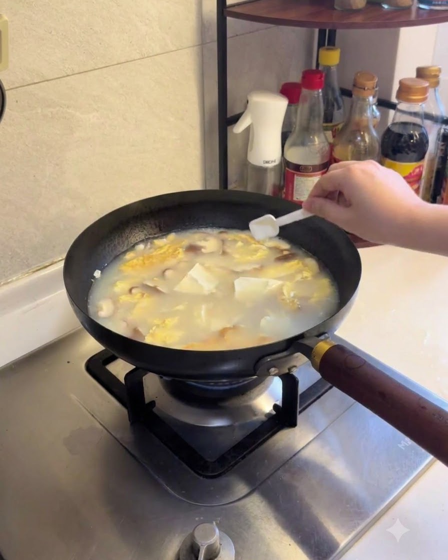 Du sel et du poivre blanc saupoudrés dans la soupe de tofu et de champignons frémissante.
