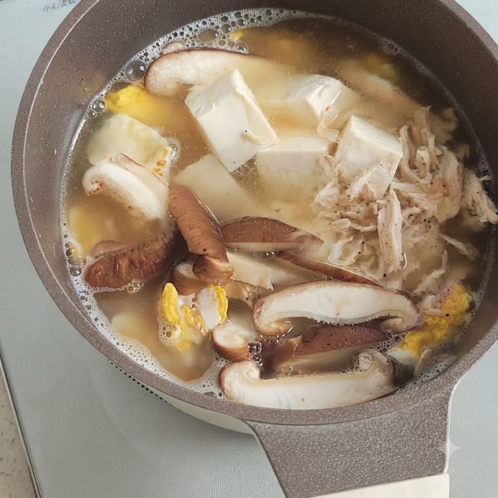 Un petit monticule de crevettes séchées reposant sur le tofu, les champignons et lœuf frémissants dans une marmite de bouillon.