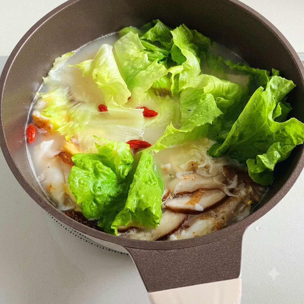 Une marmite de soupe frémissante avec des feuilles de laitue et des baies de goji rouges flottant à lintérieur.
