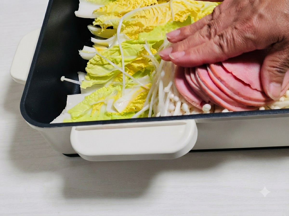 Des tranches de jambon et dautres ingrédients disposés sur les légumes dans la casserole.
