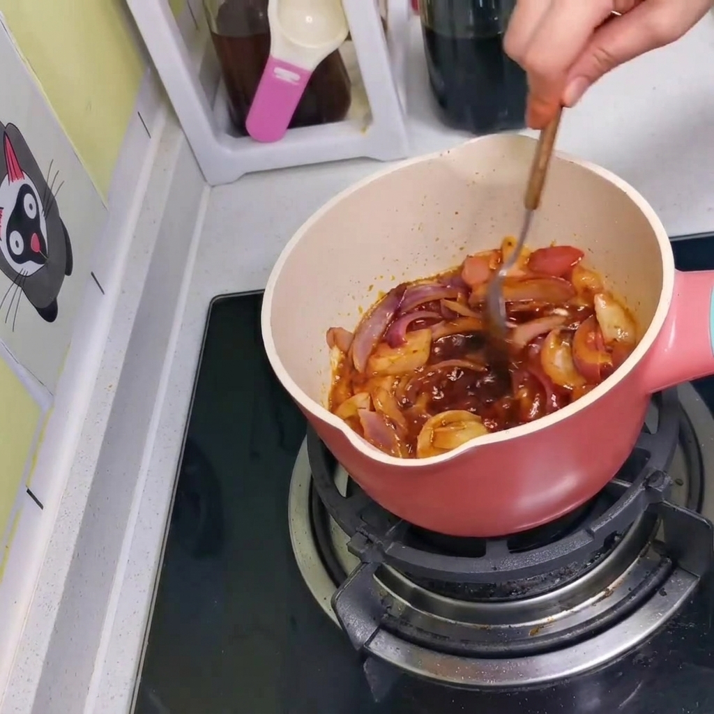 La sauce, les oignons et le kimchi mélangés ensemble dans la casserole avec une cuillère.