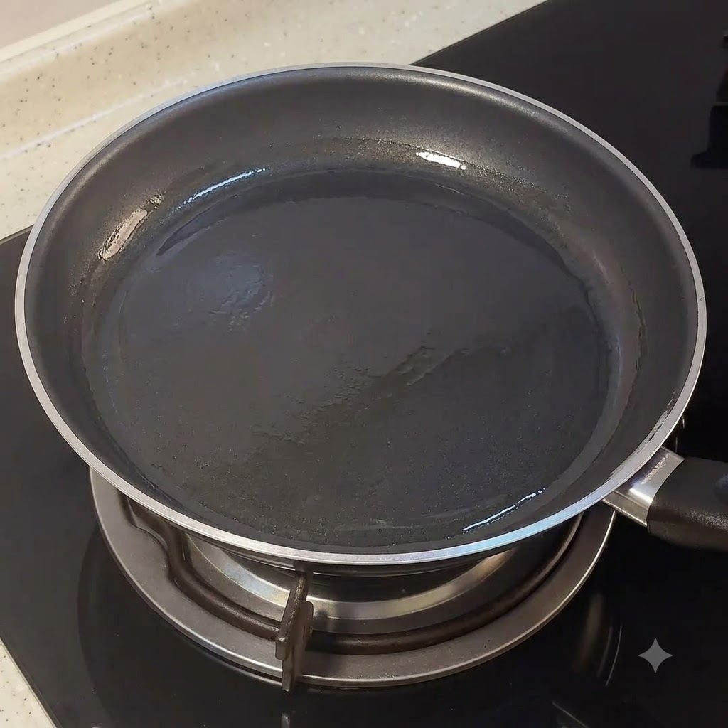 Une poêle noire vide posée sur un feu de cuisinière avec une légère couche dhuile.