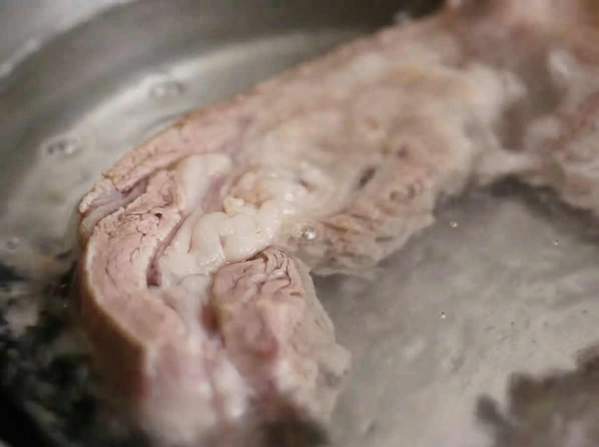 Travers de porc en train de bouillir dans leau chaude dune casserole.