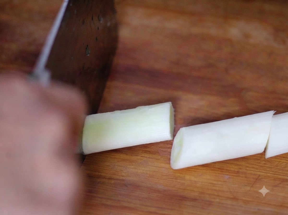 Un couteau éminçant des morceaux doignon vert sur une planche à découper en bois.
