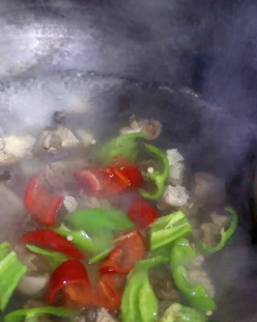 Des poivrons rouges et verts ainsi que du bok choy en train de mijoter dans leau bouillante avec les champignons.