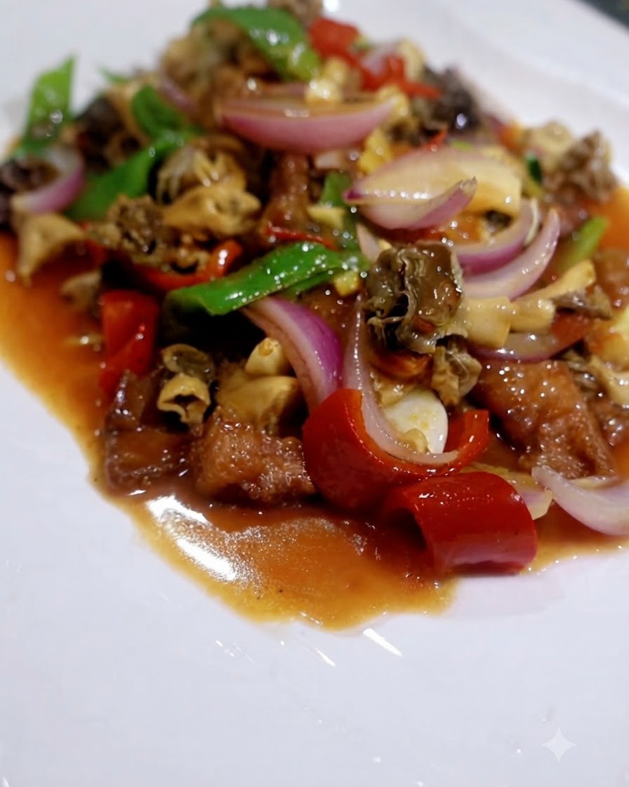 Un mélange de sauté cuit composé de champignons, de poivrons rouges, de poivrons verts et doignons dans une sauce savoureuse sur une assiette blanche.