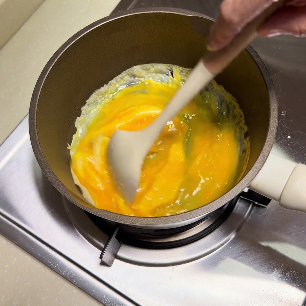 Des œufs remués et brouillés avec une spatule en silicone dans une poêle.