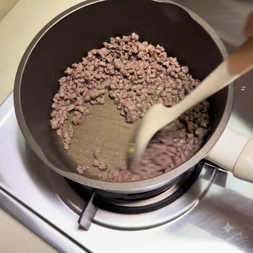 Du bœuf haché en train dêtre dorée et remué avec une spatule à lintérieur dune cocotte.