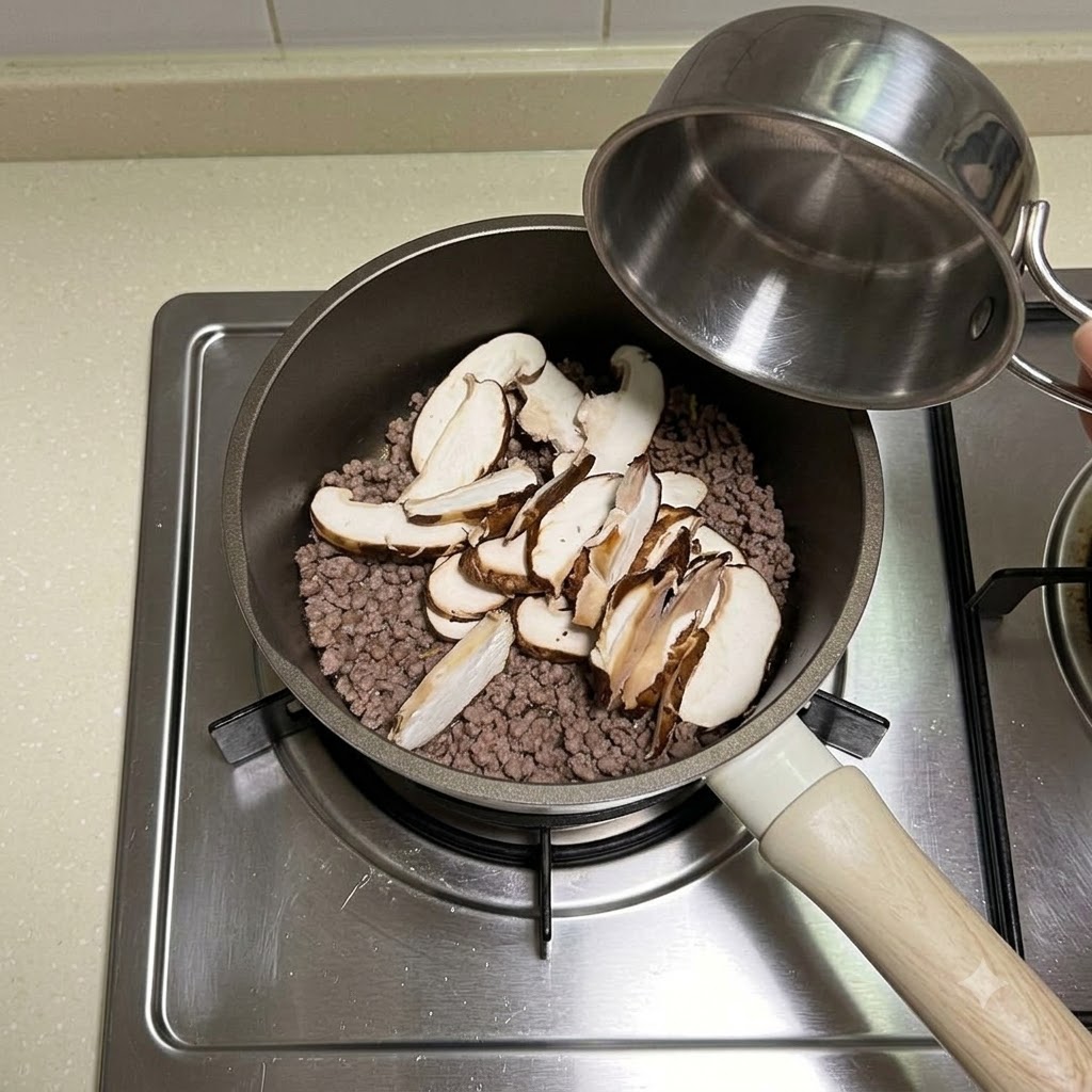 Du chou émincé frais ajouté par-dessus le bœuf et les champignons dans la poêle.