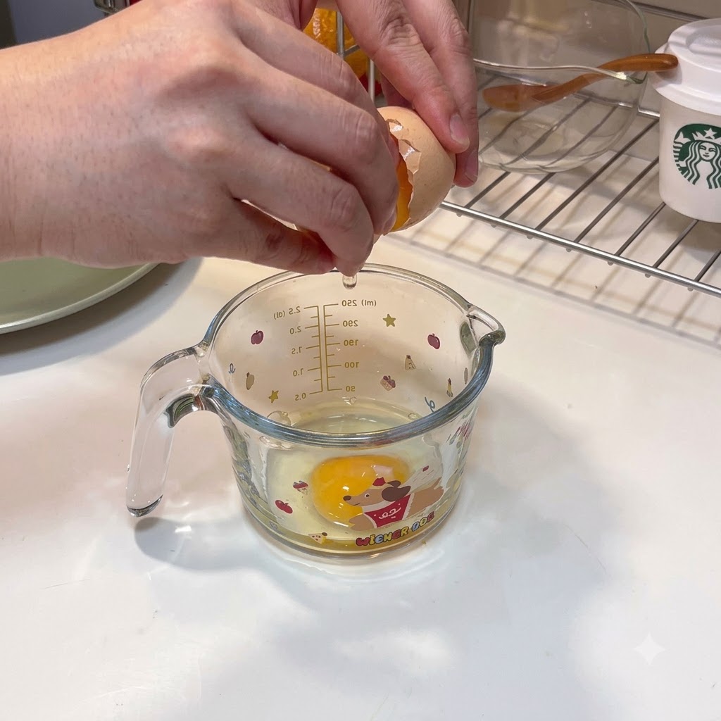 Deux œufs cassés dans une tasse à mesurer avec de leau damidon de maïs versée dedans.