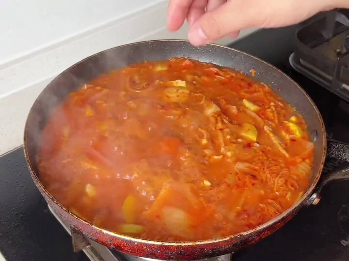 Un jaune et un blanc dœuf sinstallant dans la soupe rouge bouillonnante.