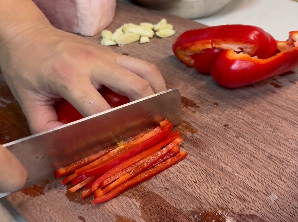 Fines tranches de porc maigre coupées sur une planche à découper en bois avec un couteau de cuisine.