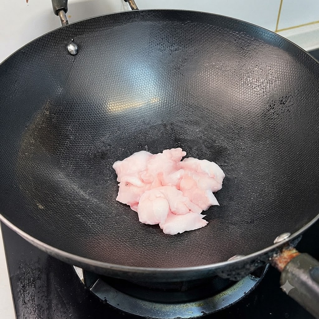 Morceaux de porc gras grésillant dans un wok noir pendant que leur graisse fond.