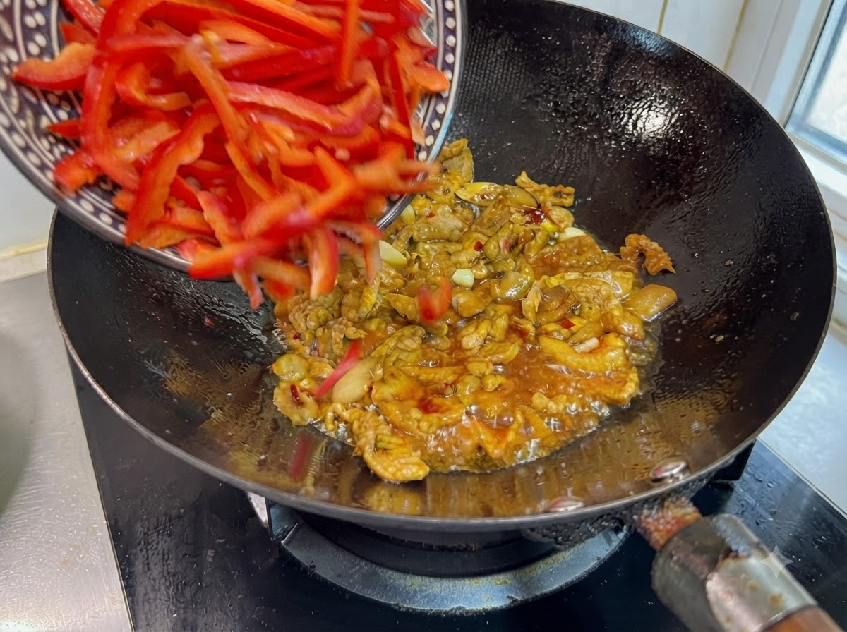Lanières de poivrons rouges doux versées dun bol à motifs dans le wok grésillant.